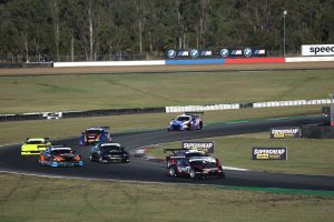 Race cars navigating a turn on a motorsport circuit during a competitive event.