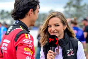 Female reporter interviewing a race car driver at a motorsport event.