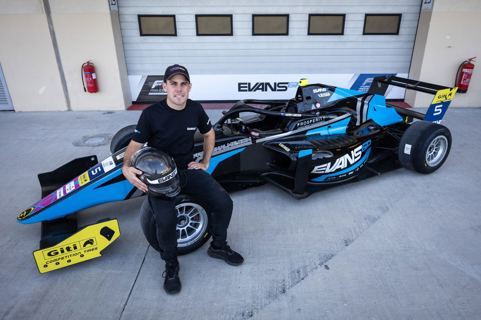 Aaron Cameron poses with the car he'll race in the Formula Regional Middle East Championship with Evans GP.