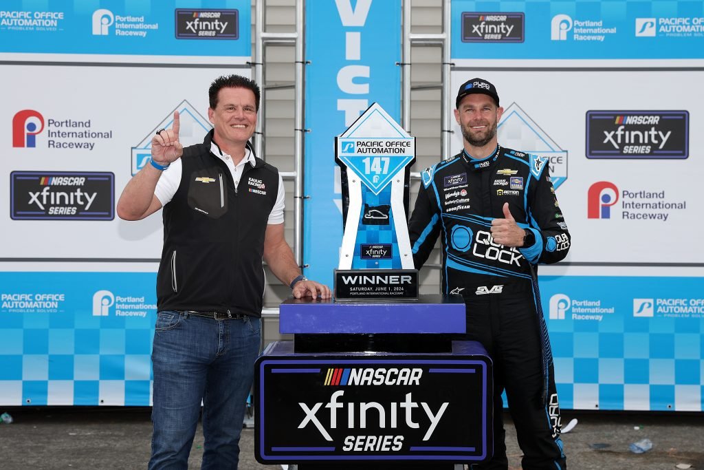 PORTLAND, OREGON - JUNE 01: Shane Van Gisbergen, driver of the #97 Quad Lock Chevrolet, celebrates with Matt Kaulig, owner of Kaulig Racing in victory lane after winning the NASCAR Xfinity Series Pacific Office Automation 147 at Portland International Raceway on June 01, 2024 in Portland, Oregon. (Photo by Meg Oliphant/Getty Images)