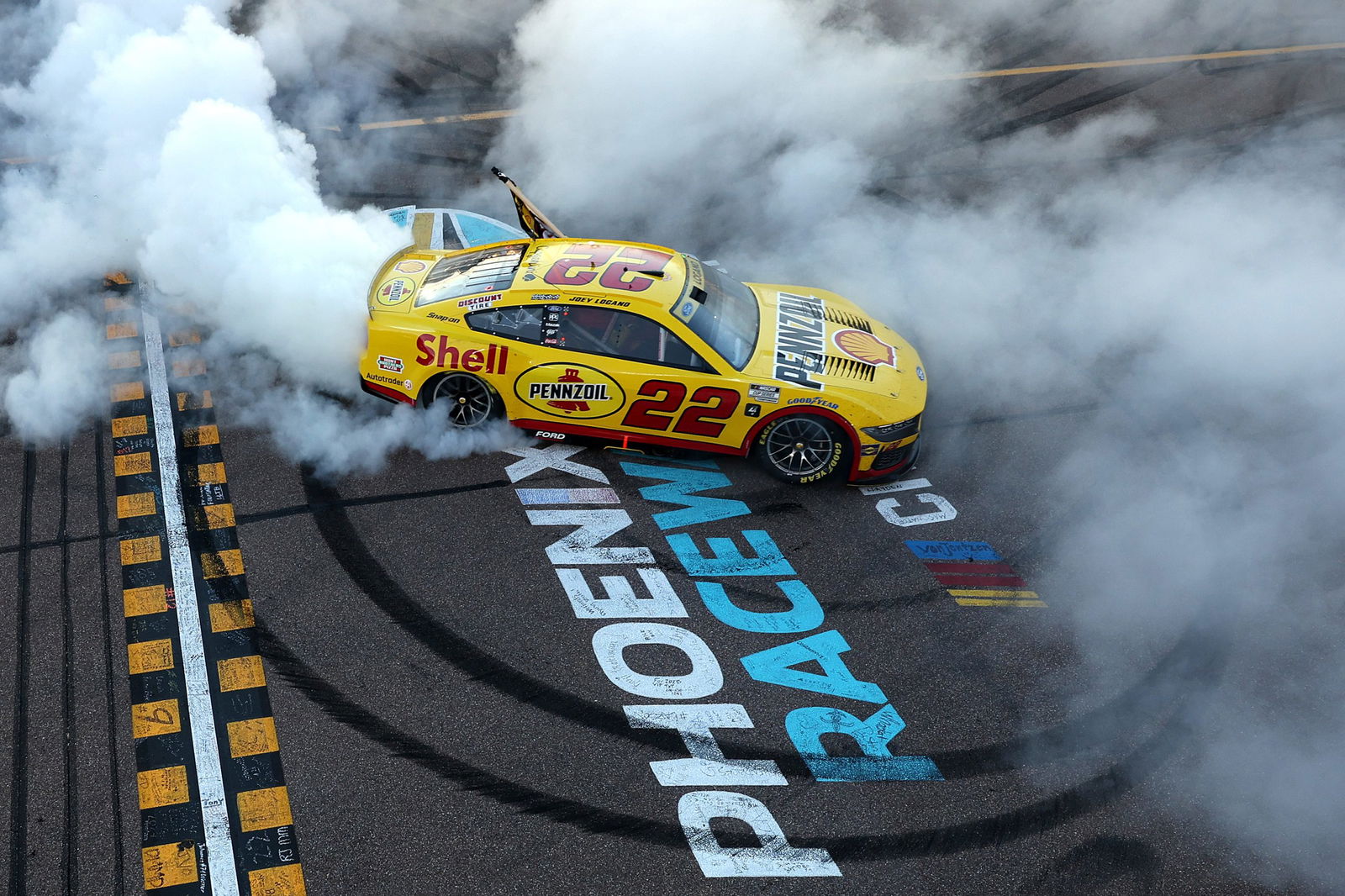 Joey Logano, driver of the #22 Shell Pennzoil Ford, celebrates with a burnout after winning the NASCAR Cup Series Championship Race at Phoenix Raceway. 