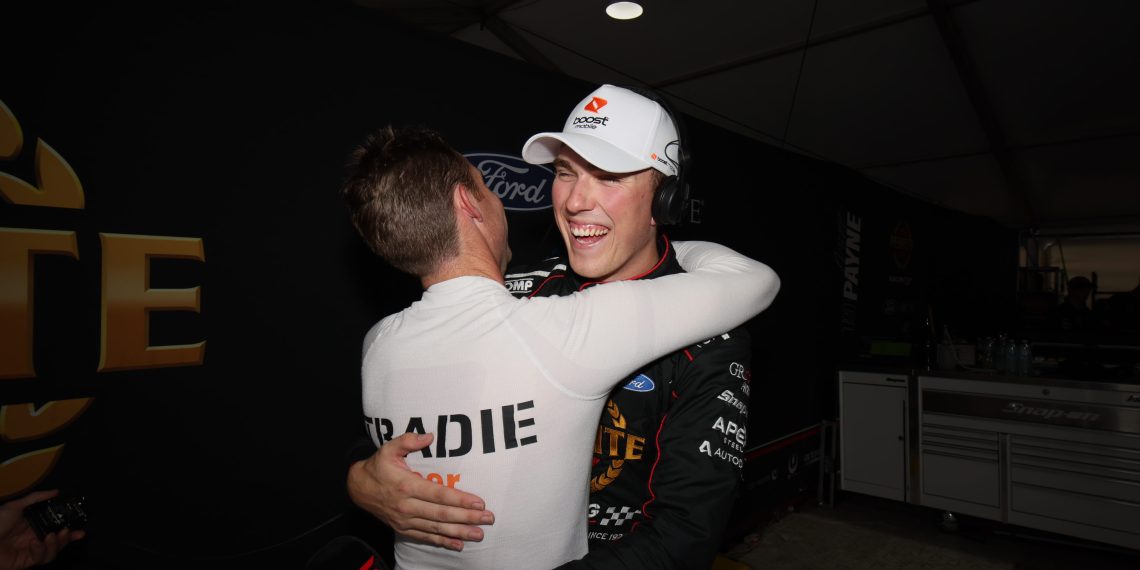 Hat-exempt driver David Reynolds embraces pole winner Matt Payne wearing a Boost Mobile hat. Image: Supercars