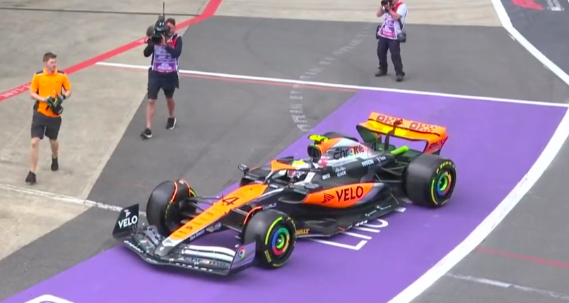 A McLaren mechanic retrieves a fan from the exhaust on Lando Norris' car