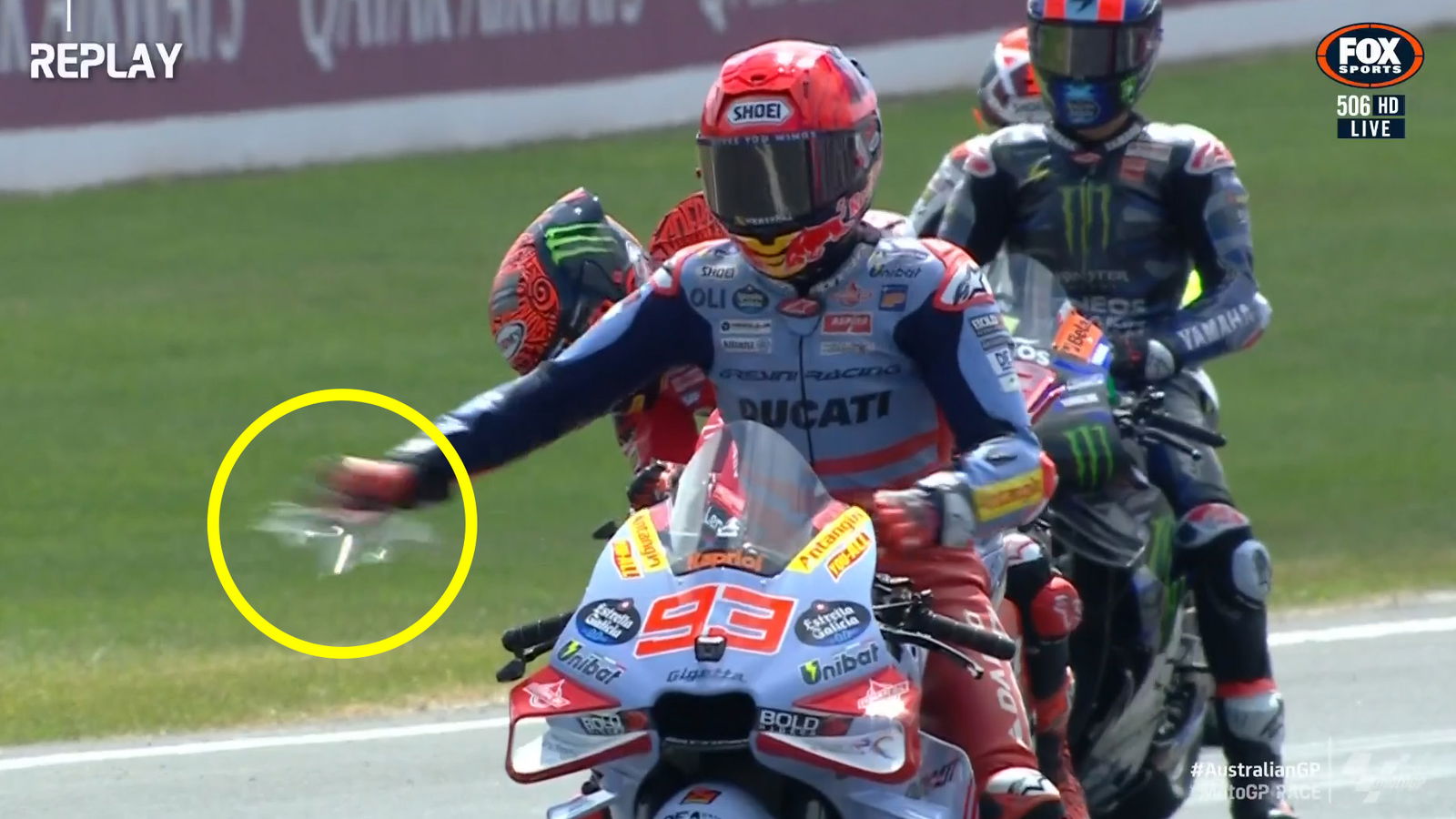 Marc Marquez pulls a tear-off (circled) that landed under his rear wheel.