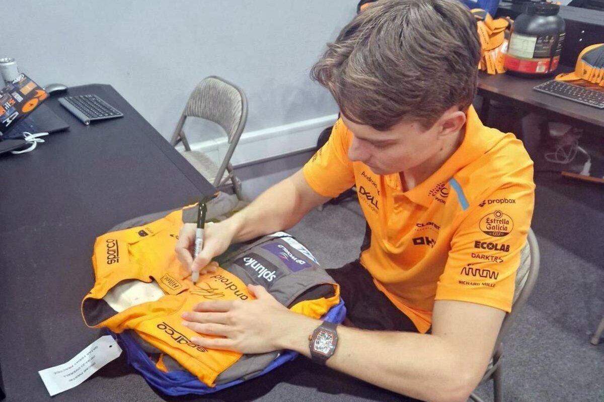 Oscar Piastri signing the suit up for auction. Image: McLaren